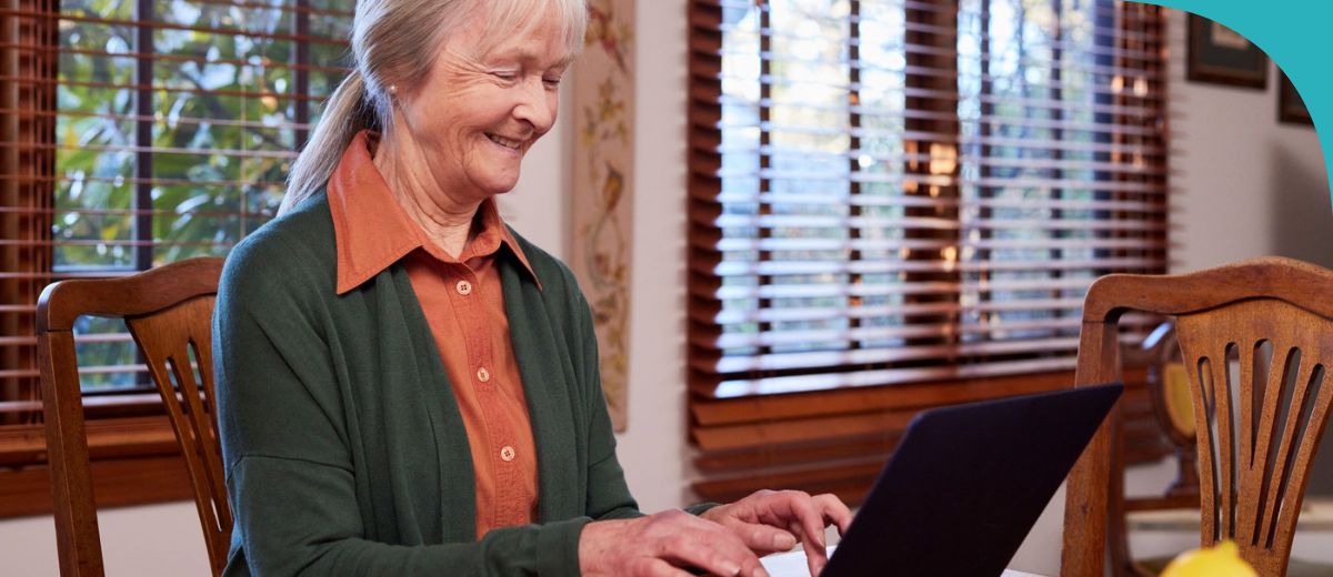 An older lady typing on her laptop
