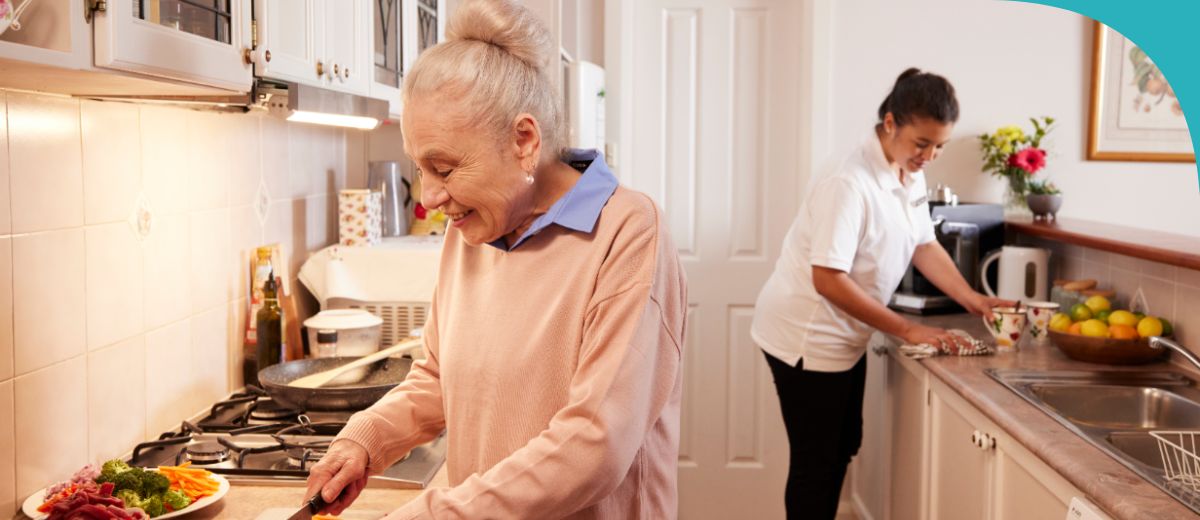 An older lady cooking in the kitcehn and a younger woman cleaning the kitchen