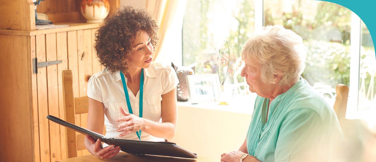 An older lady talking to a younger lady who is holding a folder