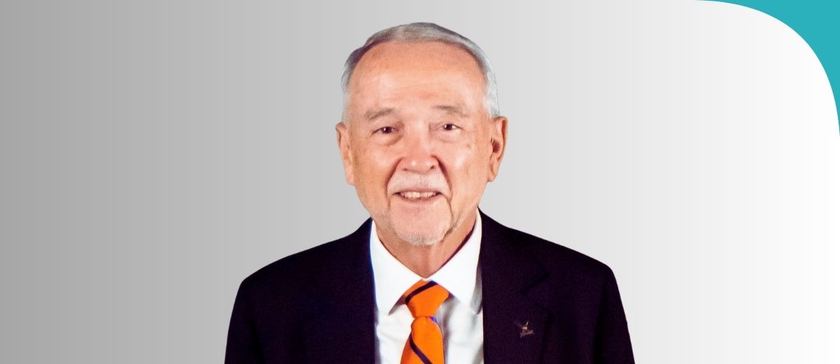 A protrait of a man wearing an orange tie