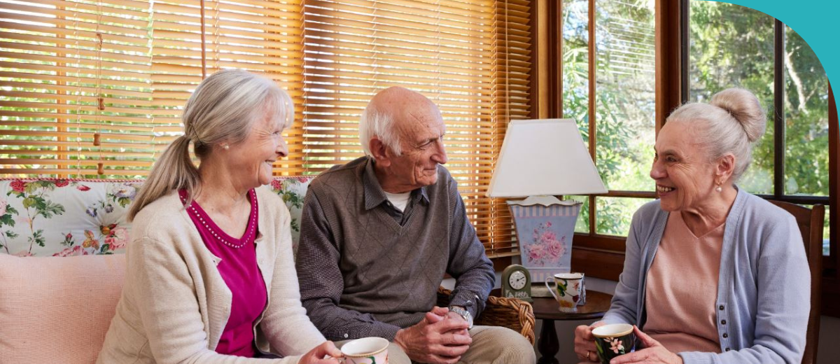 Three people sitting in a lougeroom enjoying a cup of tea