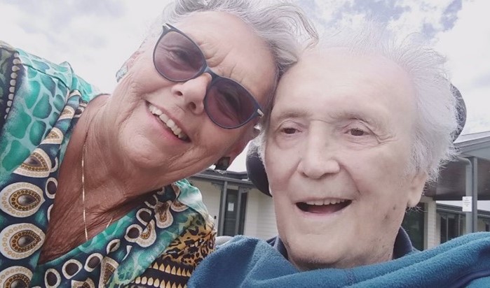 A selfie of two older people smiling at the camera